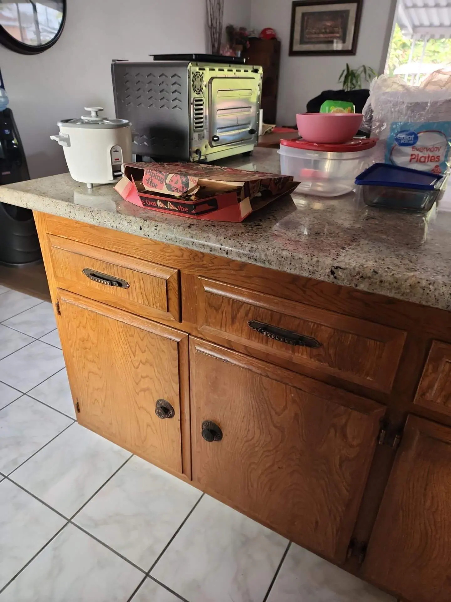 Kitchen island with original oak cabinets and speckled laminate countertop prior to refinishing, showing dated wood cabinetry and hardware before a professional cabinet painting update.