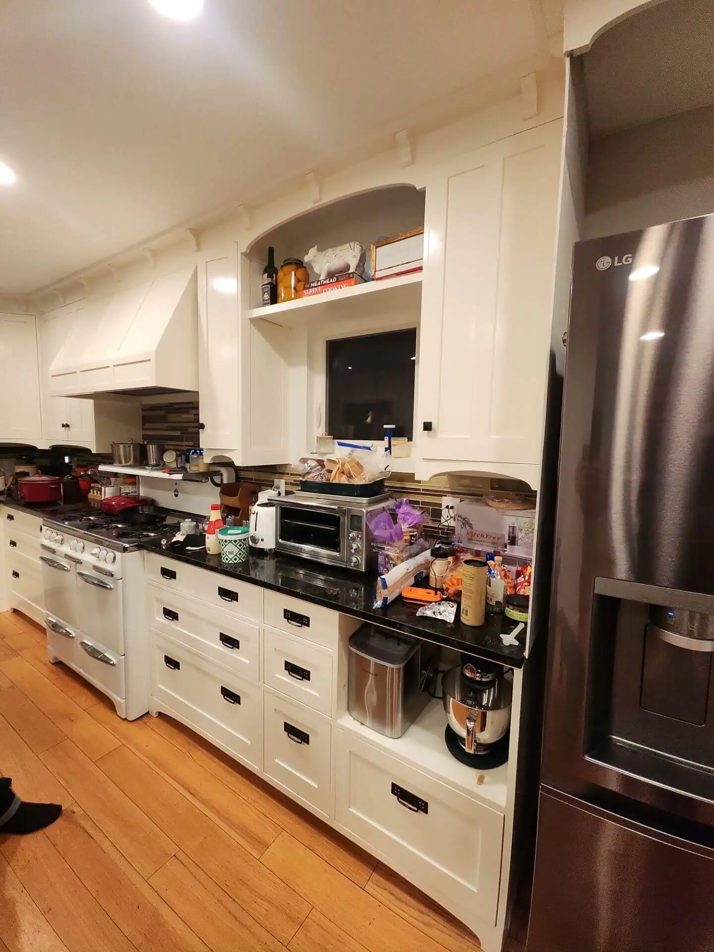 Bright white kitchen cabinets with a classic shaker-style design and black hardware, refinished for a clean, modern look by Sucro Painting Contractors as part of a detailed kitchen painting project.