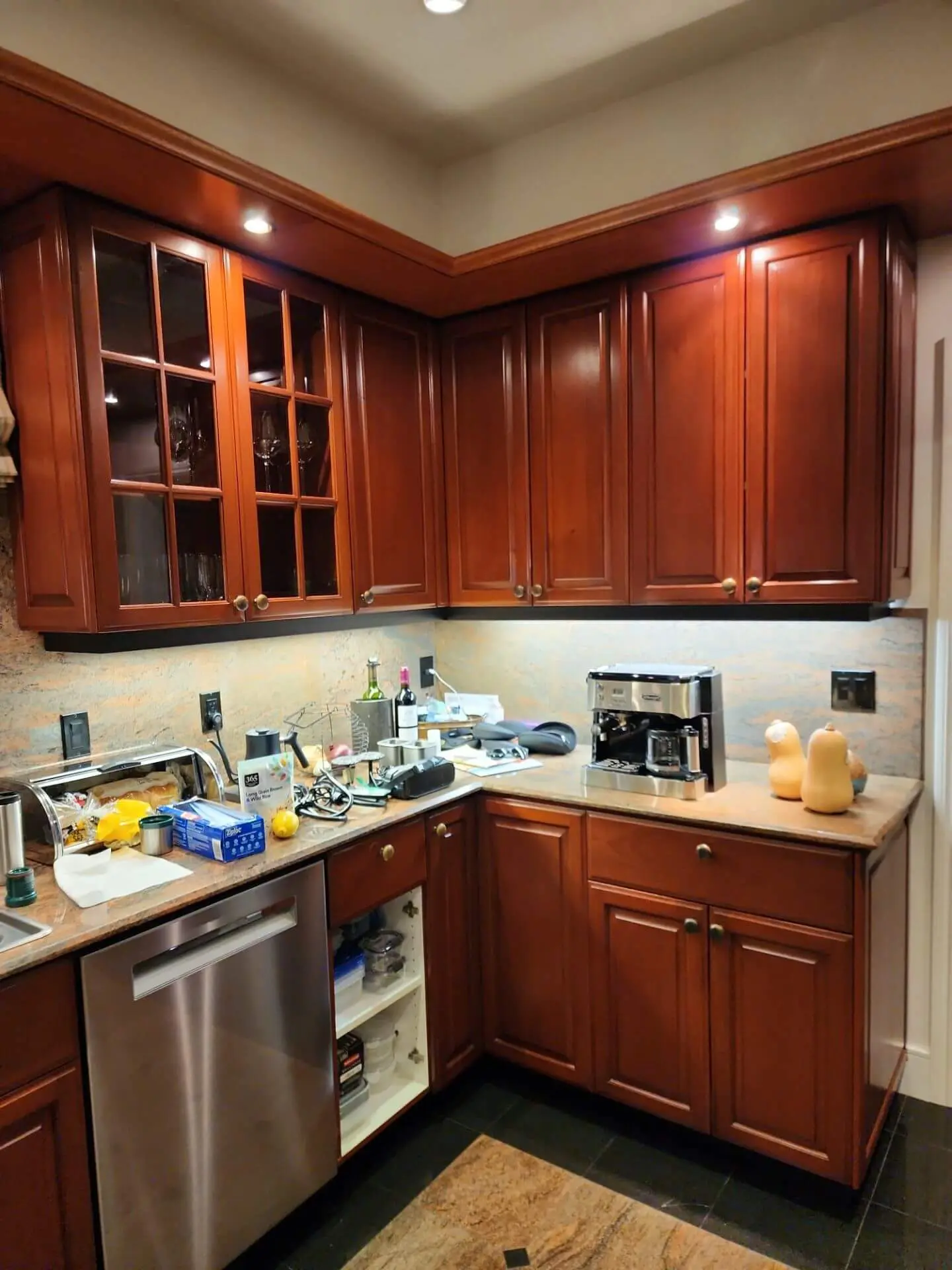 Rich cherry wood kitchen cabinets with a smooth, refreshed finish and under-cabinet lighting, showcasing professional cabinet painting and refinishing work by Sucro Painting Contractors.