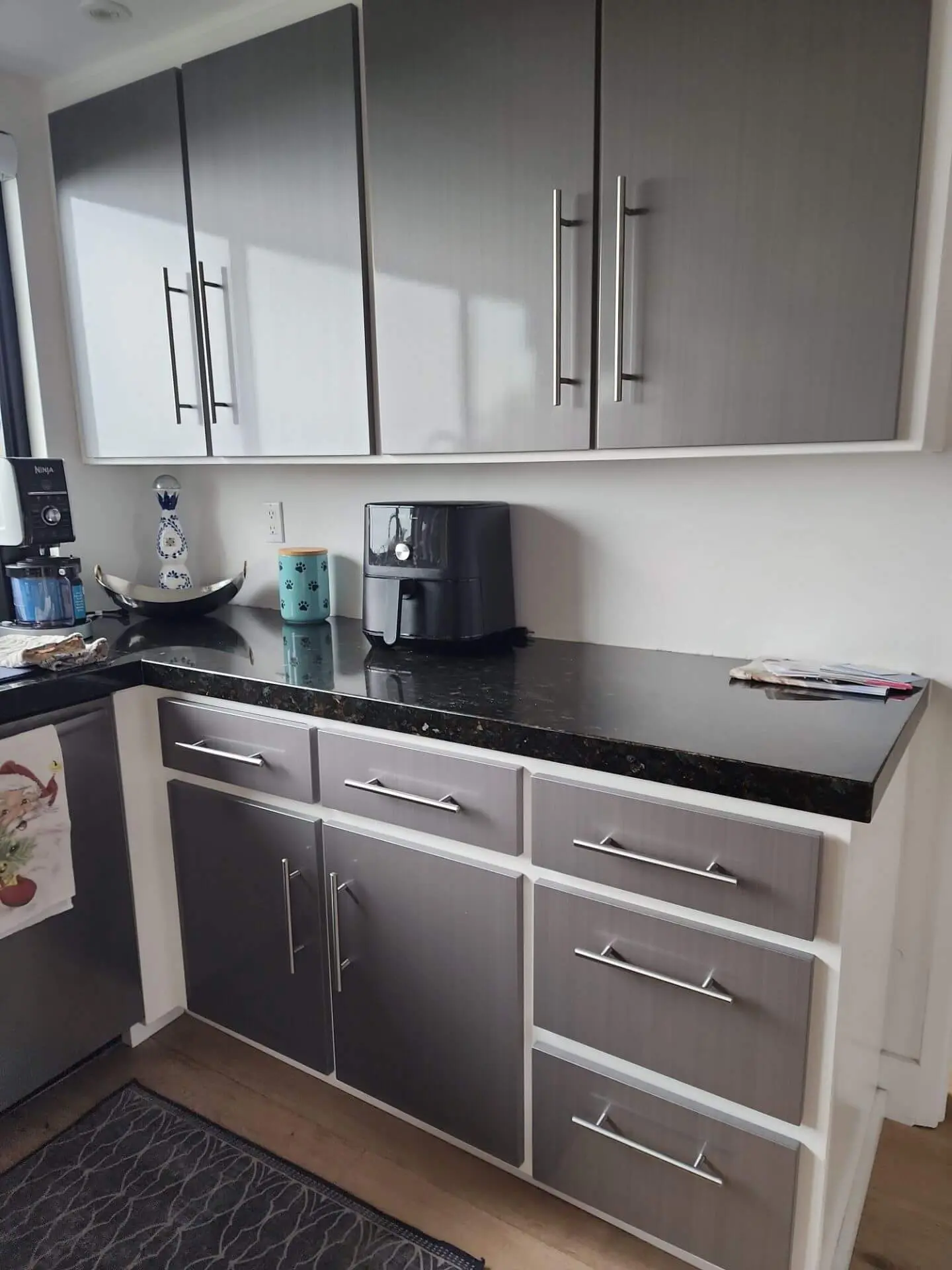 Modern gray kitchen cabinets with clean white framing and black stone countertop, highlighting detailed cabinet refinishing and interior paint work completed by Sucro Painting Contractors.