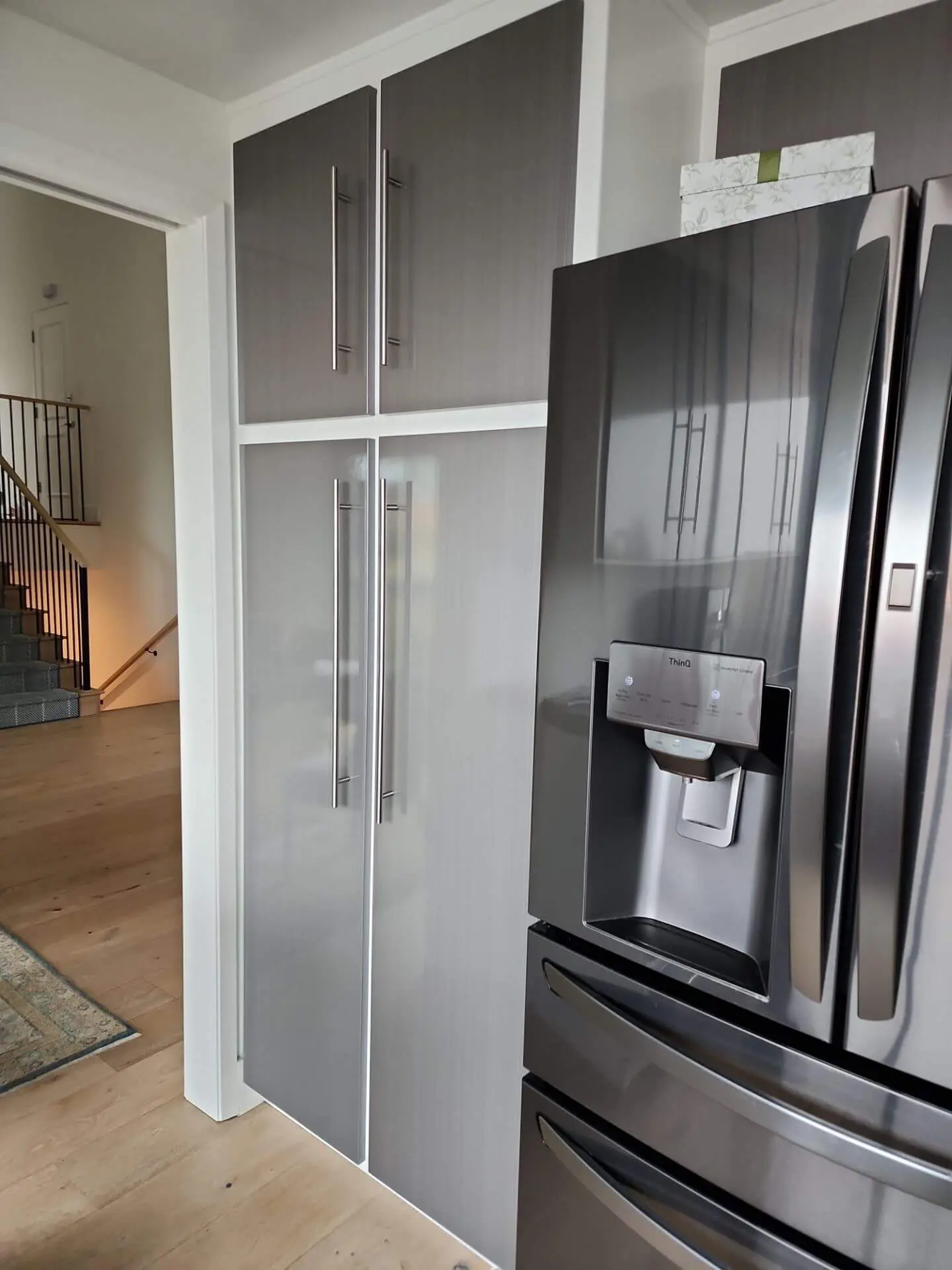 Sleek gray kitchen cabinetry with modern hardware and stainless steel refrigerator, showcasing detailed cabinet finishing and interior paint work by Sucro Painting Contractors.