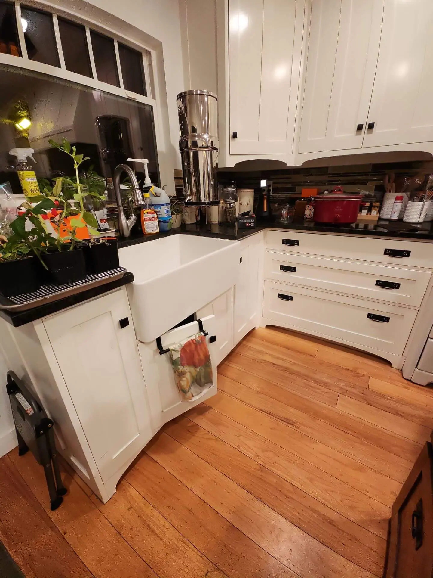 Bright farmhouse-style kitchen with crisp white cabinetry and a deep apron-front sink, showcasing a clean, professional cabinet painting and refinishing project completed by Sucro Painting Contractors.