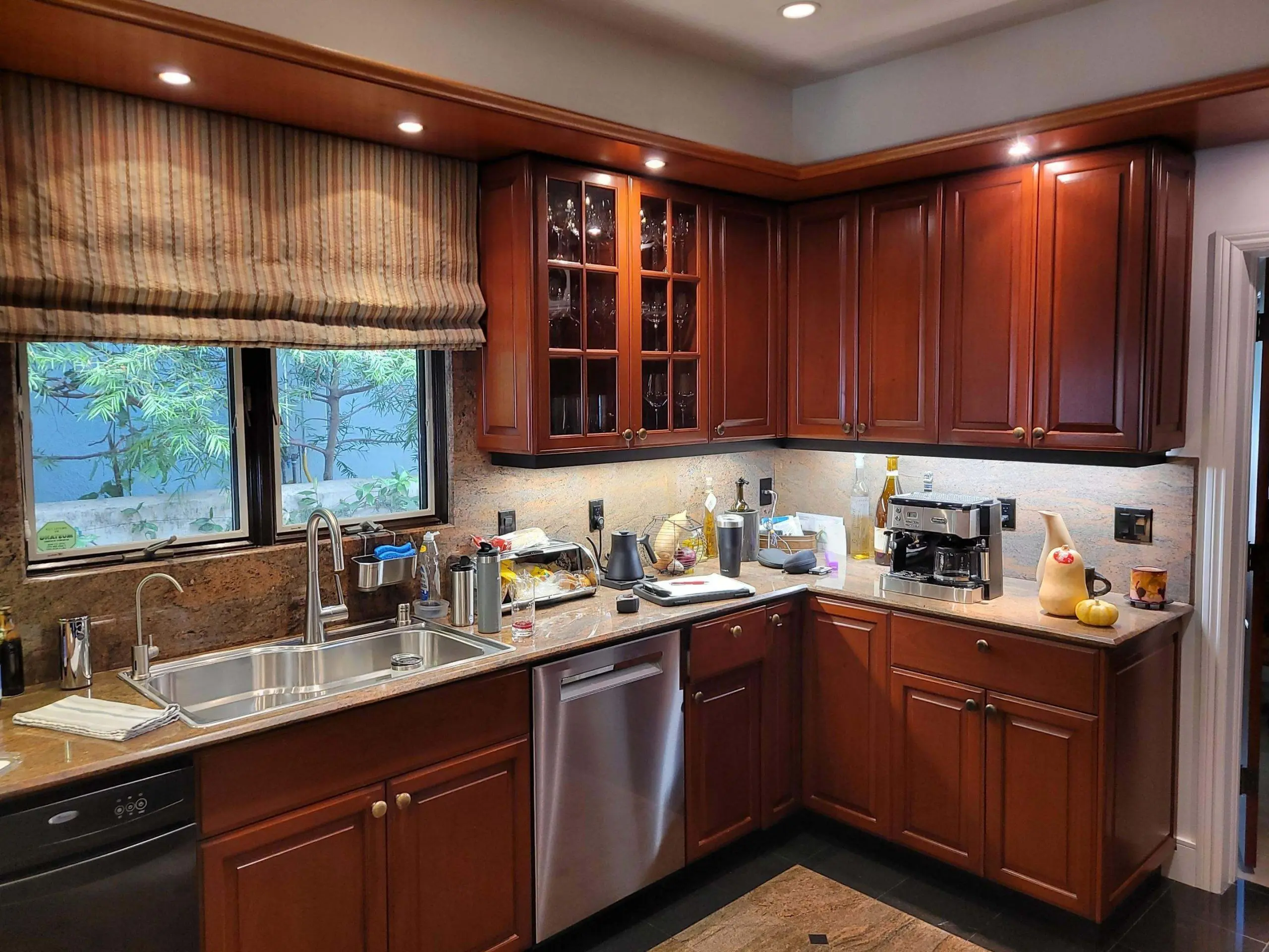 Warm kitchen interior featuring rich wood cabinetry and granite countertops, highlighting a professionally completed interior cabinet painting and refinishing project by Sucro Painting Contractors.