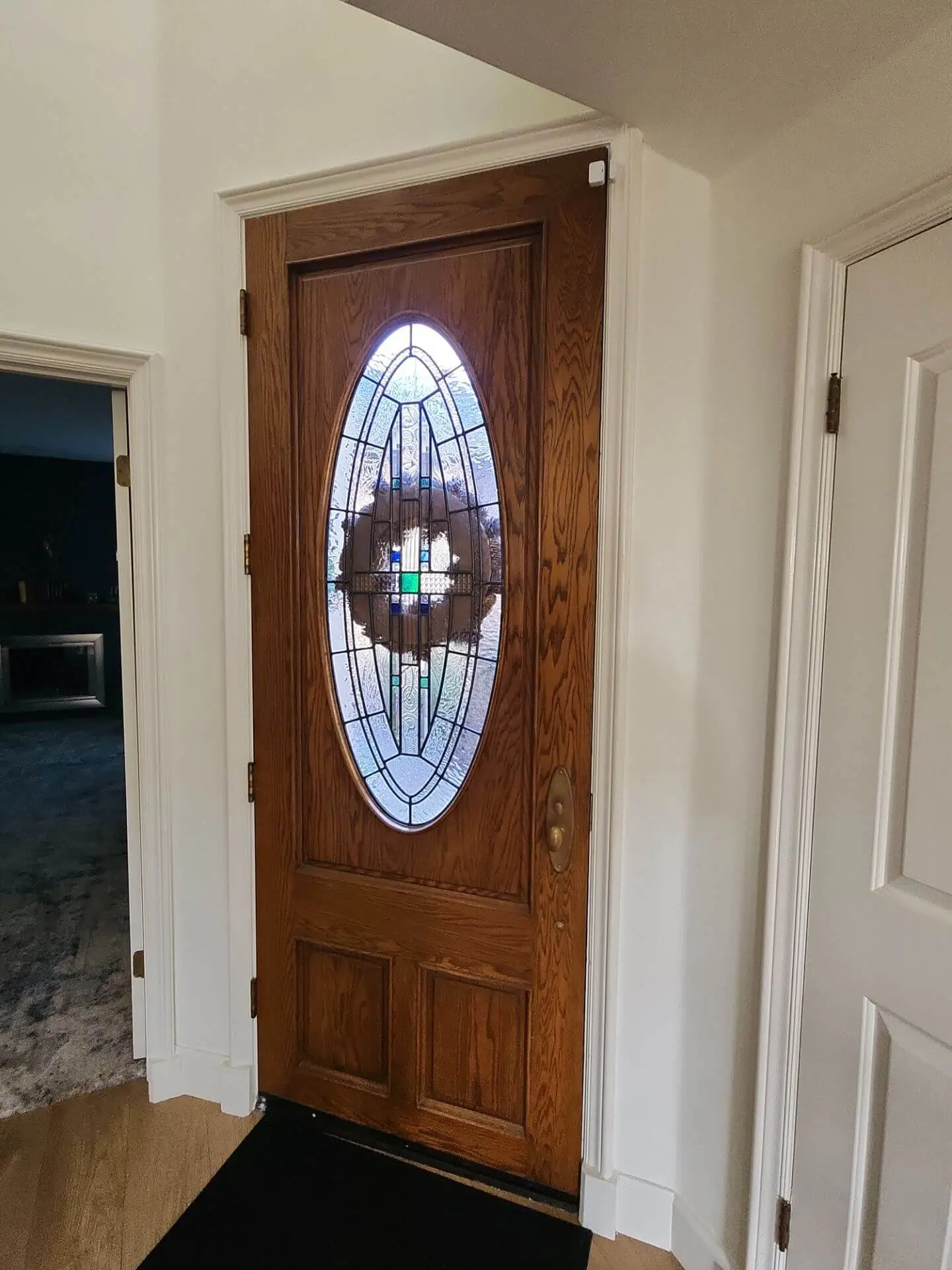 Refinished wood front door with decorative glass insert and freshly painted white trim, completed as part of a detailed interior painting project by Sucro Painting Contractors.