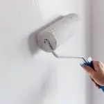 Paint roller applying white paint to an interior wall