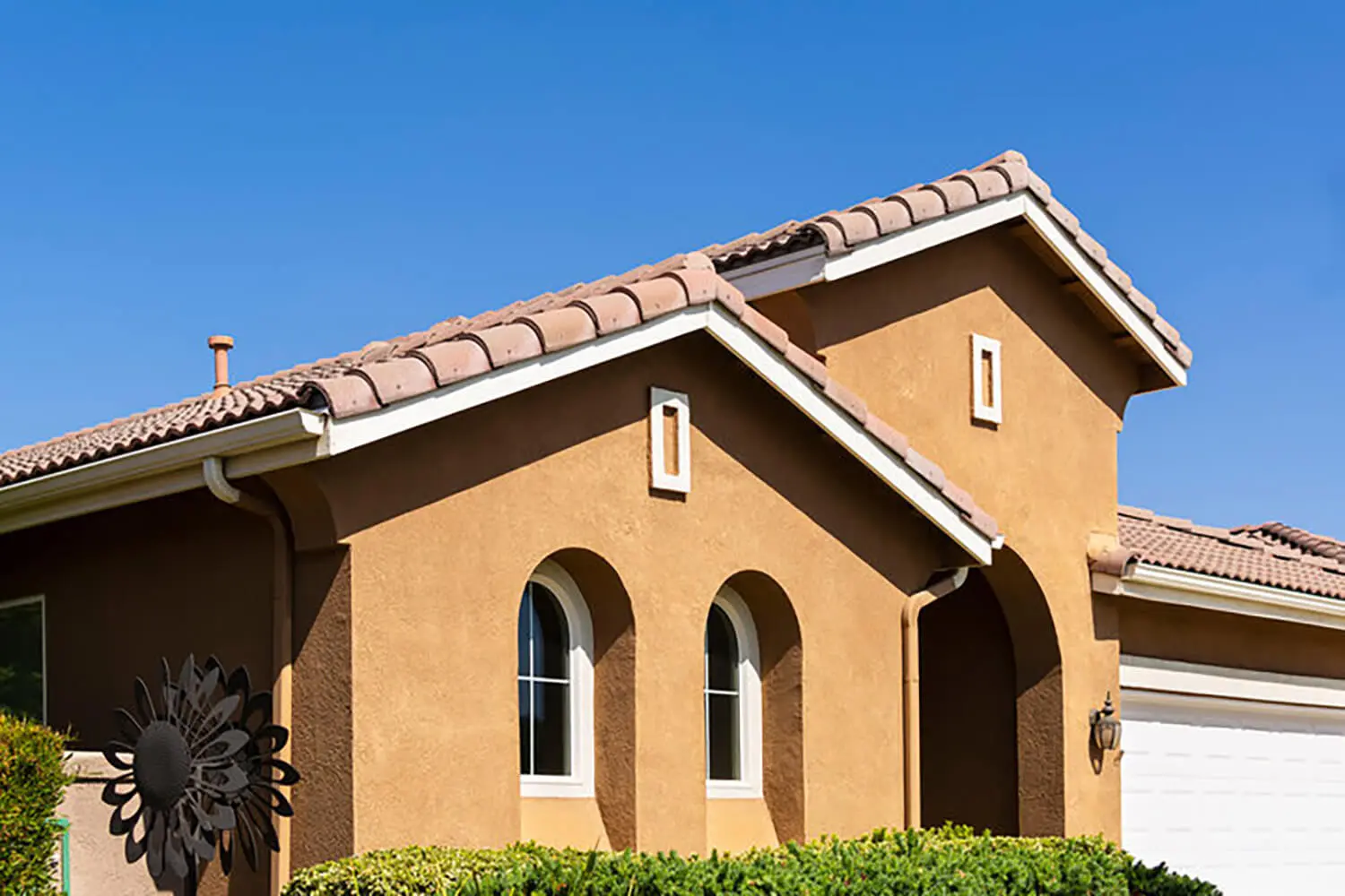 Stucco exterior on a Southern California home with clay tile roof and arched windows