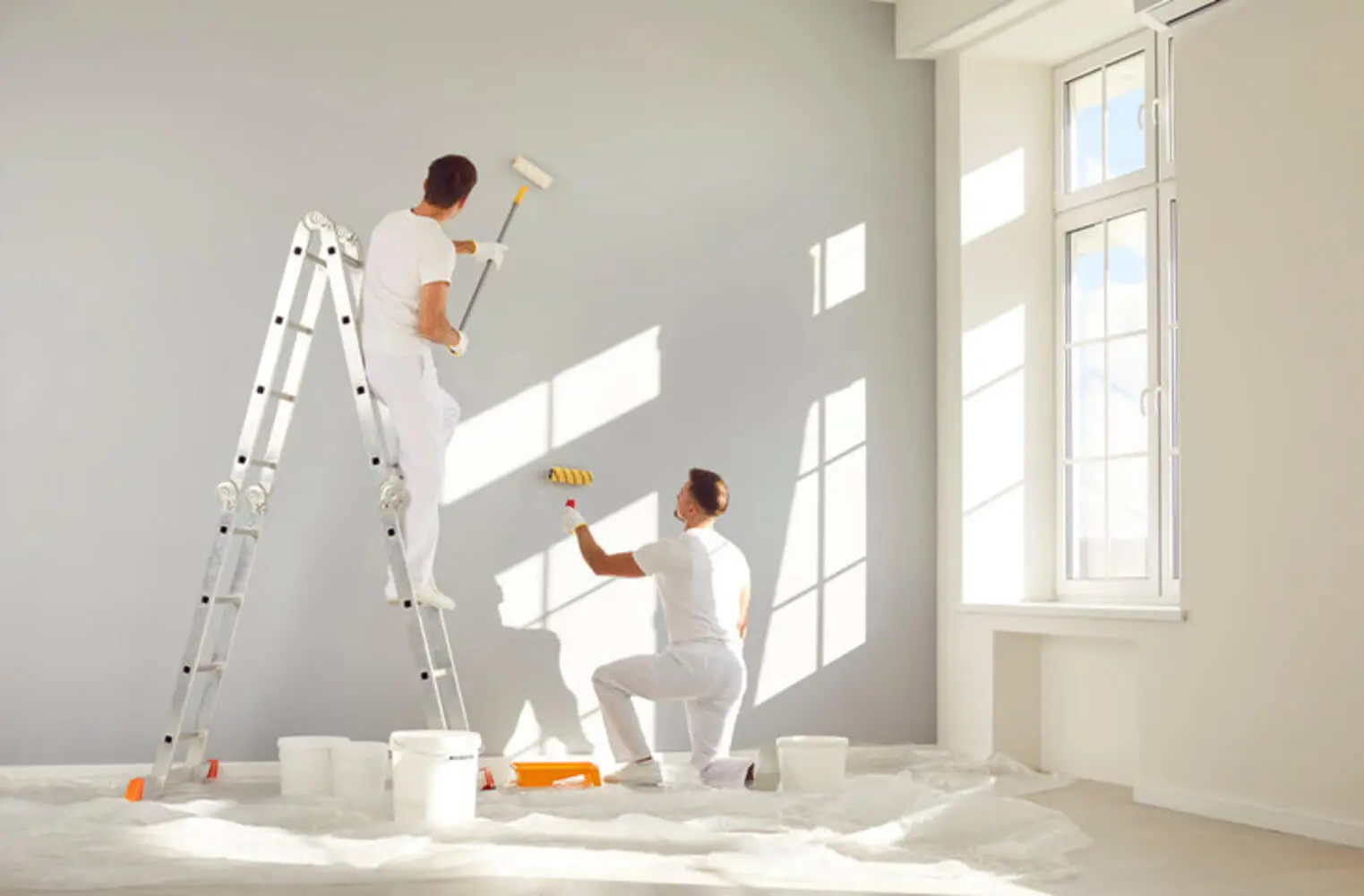 Two commercial painters working together to repaint an interior office wall