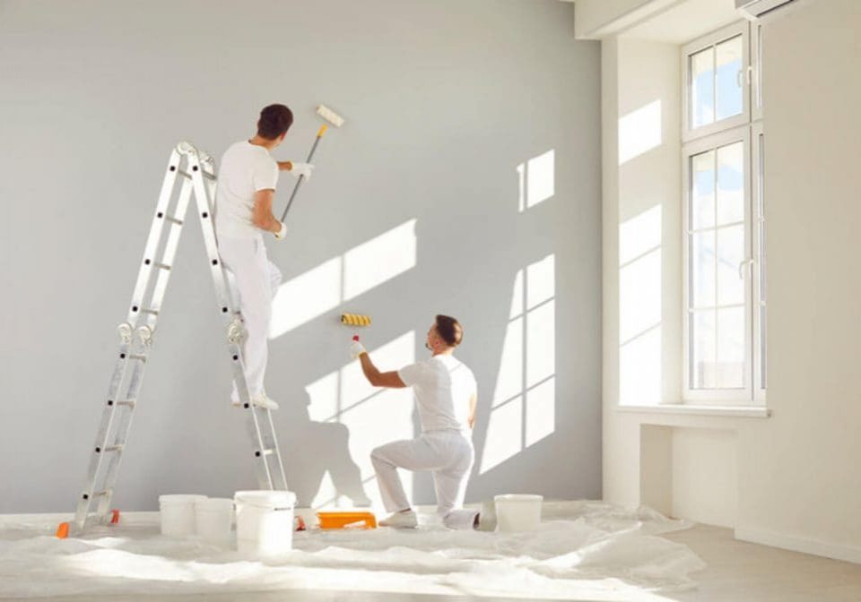 Two commercial painters working together to repaint an interior office wall