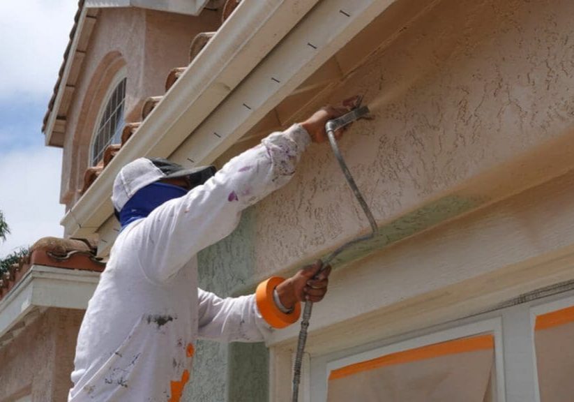 Professional painter applying protective stucco coating to prevent exterior paint peeling on a South Bay home